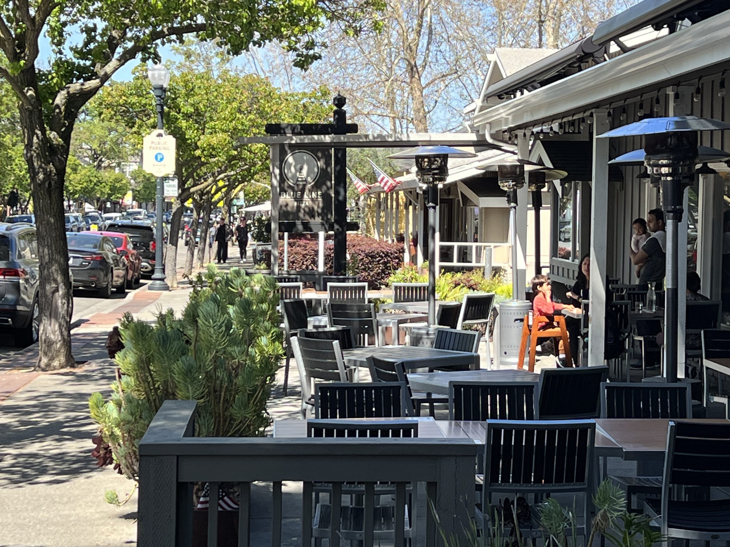 A street view of tables and chairs on the sidewalk.