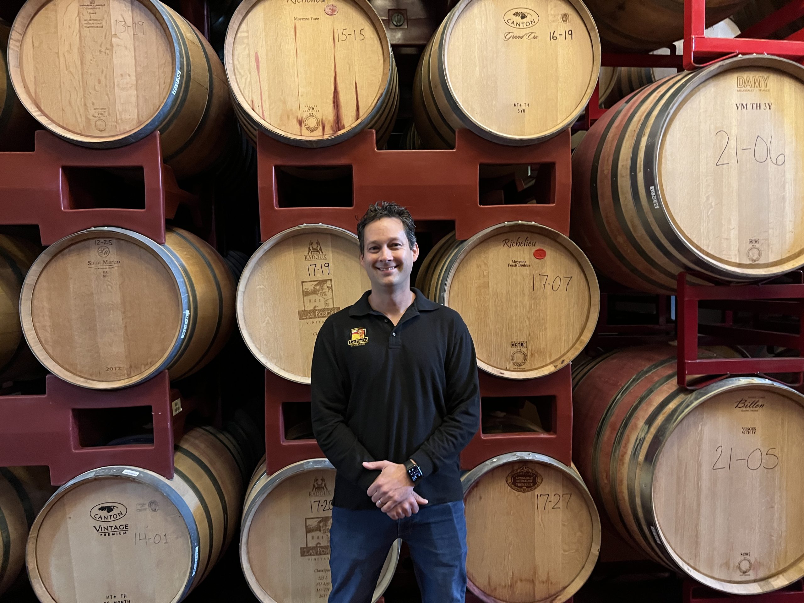 A man standing in front of some wine barrels.