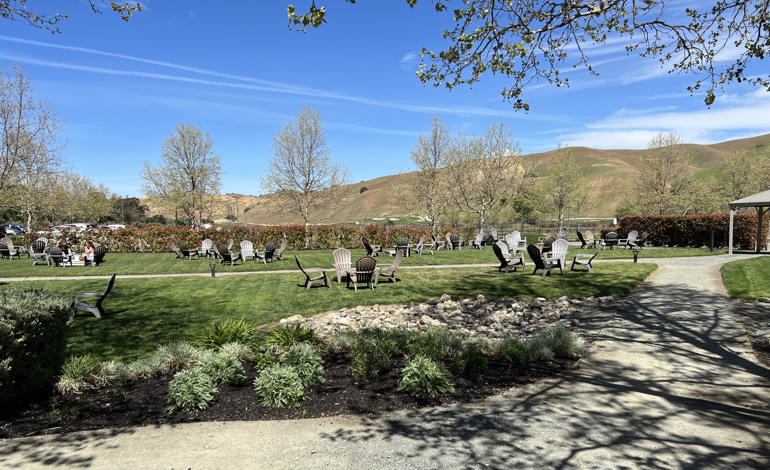 A group of people sitting on benches in the grass.