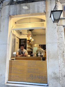 Two men are standing behind a counter in front of a building.