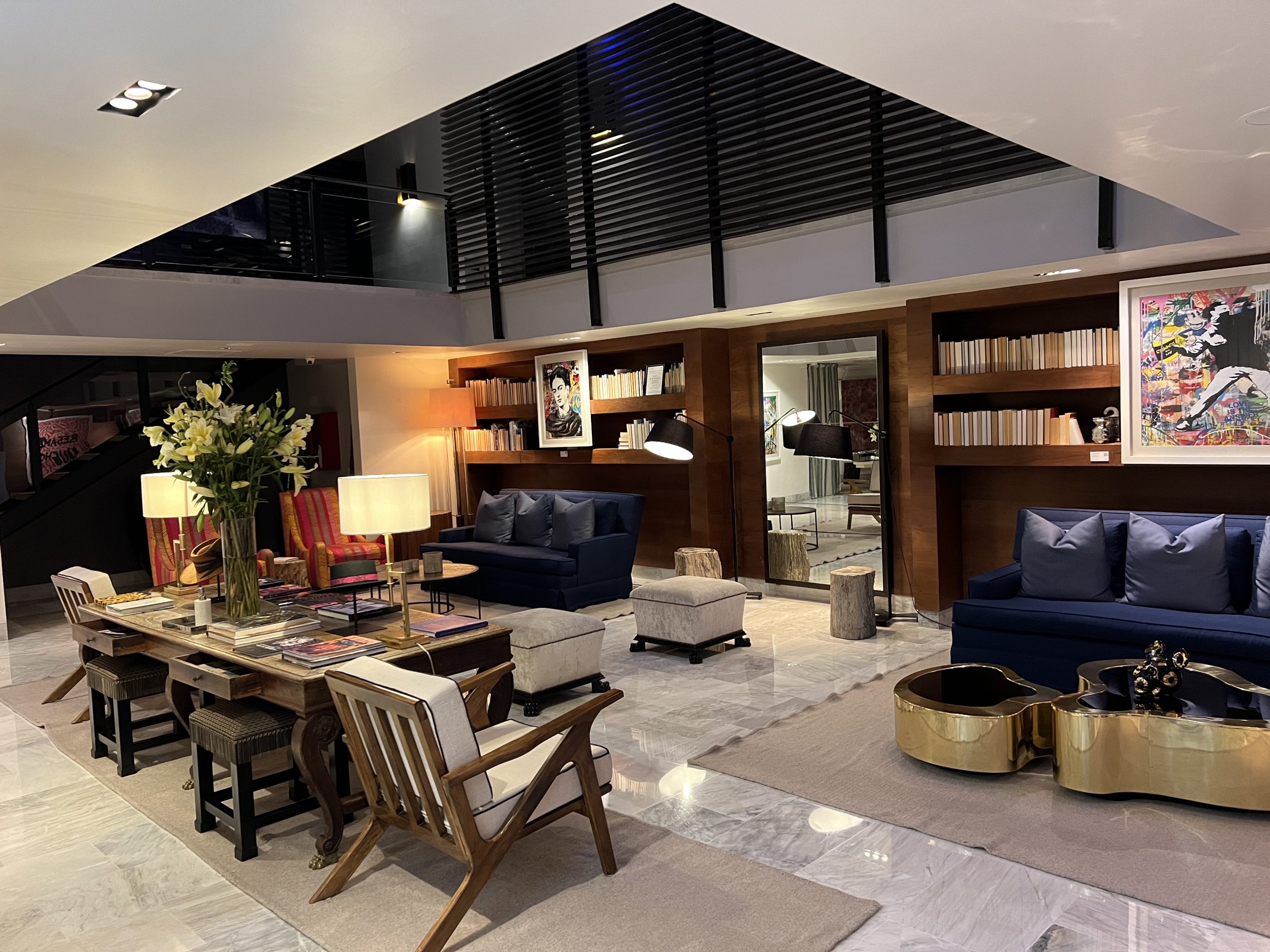 A living room with chairs, tables and a bookshelf.