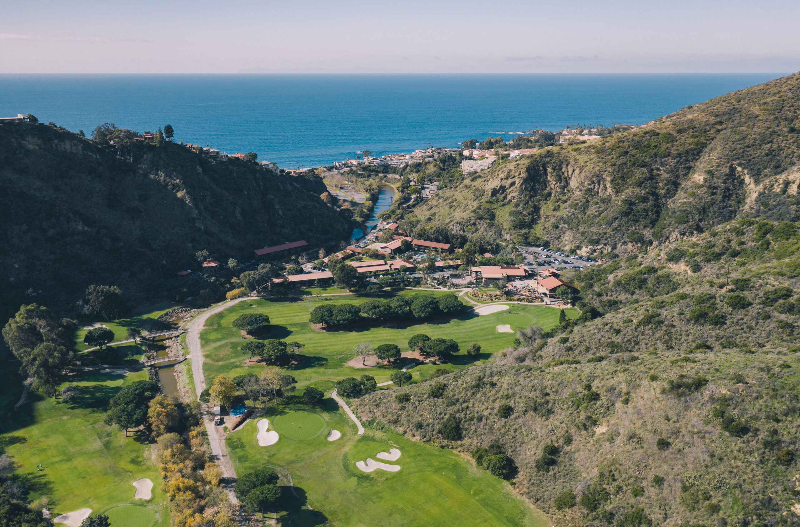 A view of the ocean from above shows a golf course.