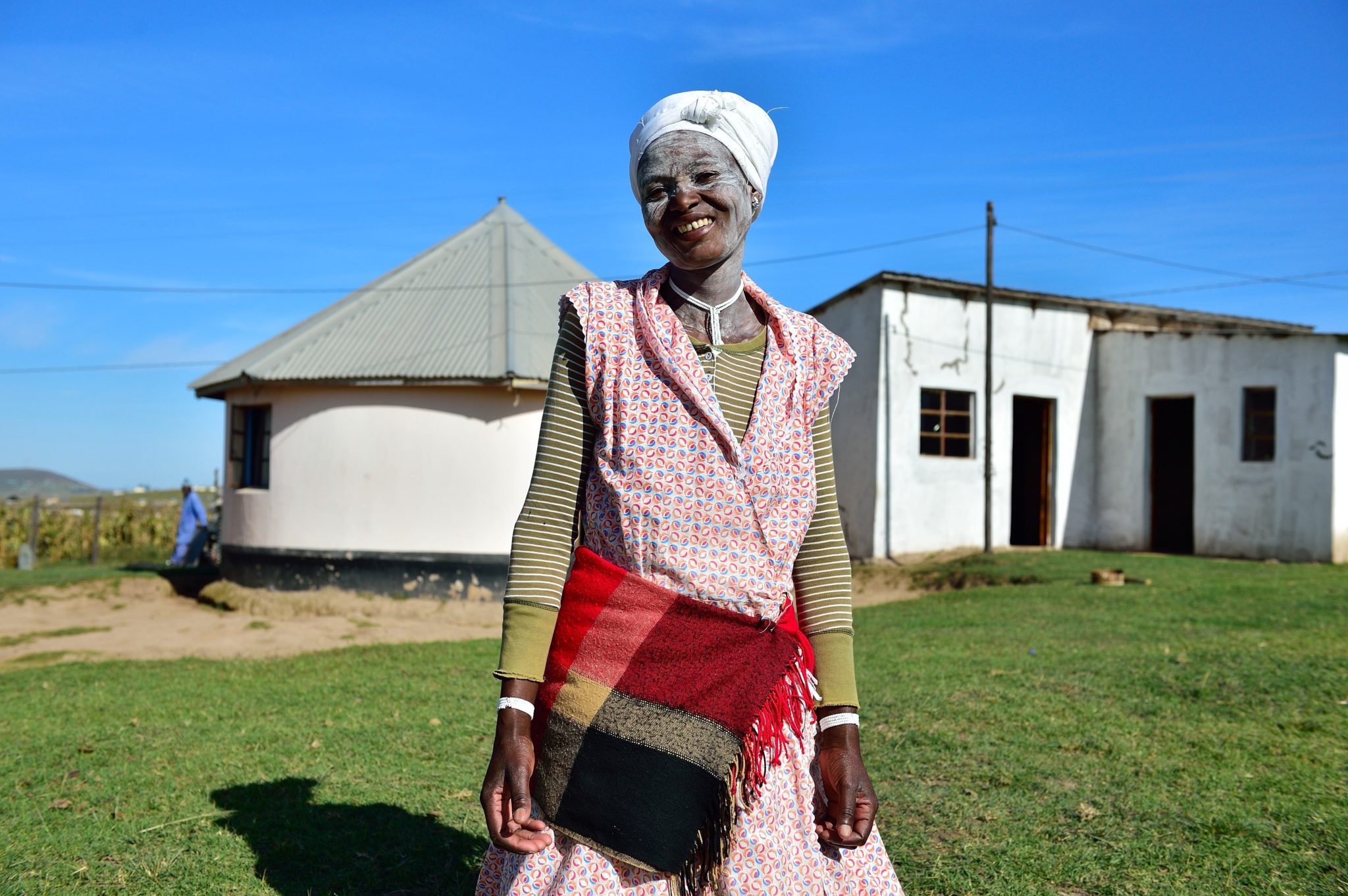 A woman in traditional dress standing outside of a house.