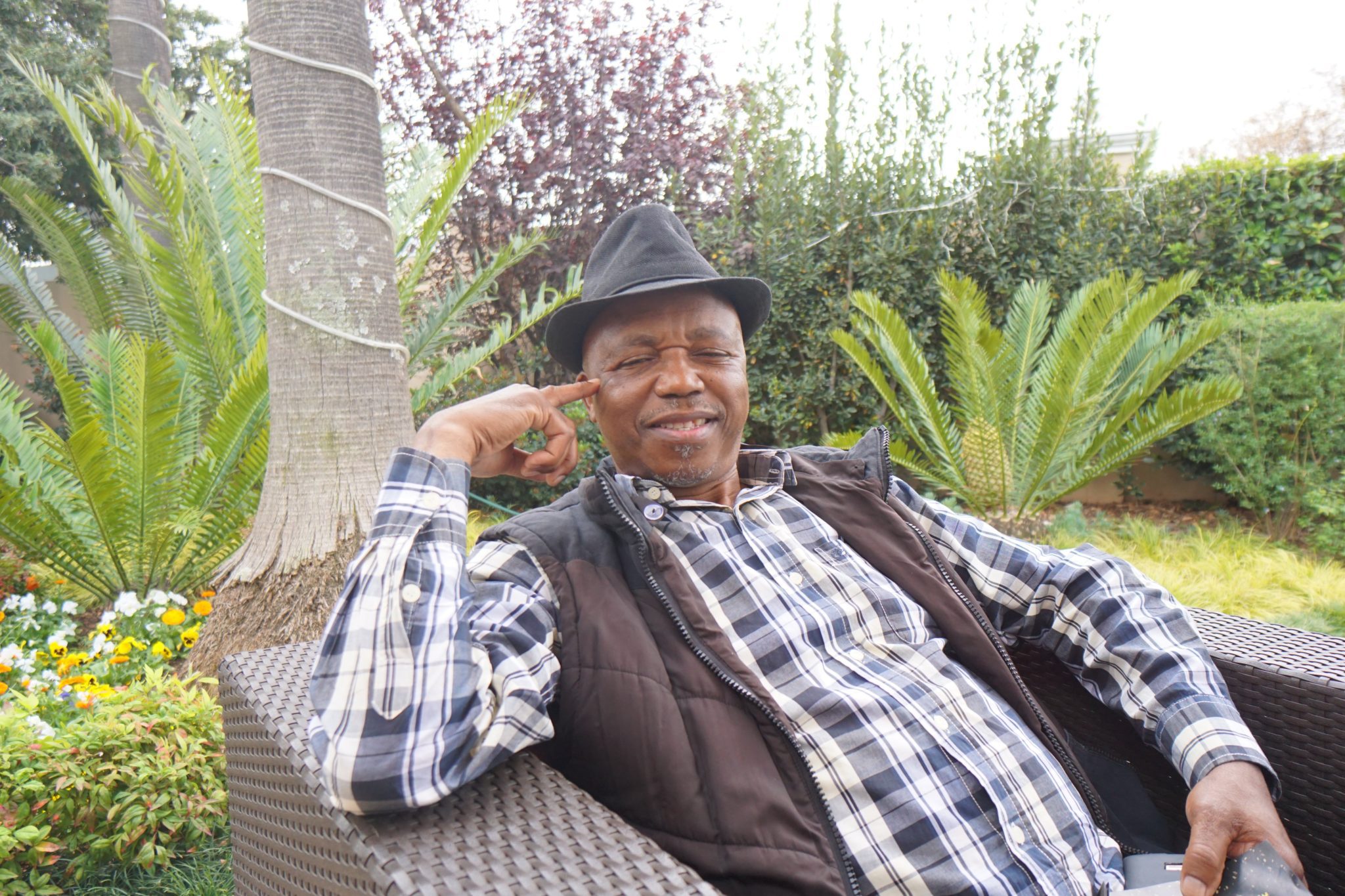 A man sitting on top of a bench wearing a hat.