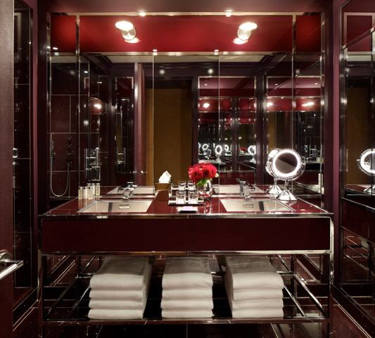 A bathroom with red walls and a large mirror.