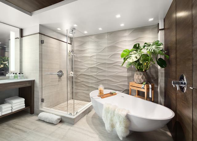 A bathroom with a tub, shower and plants.