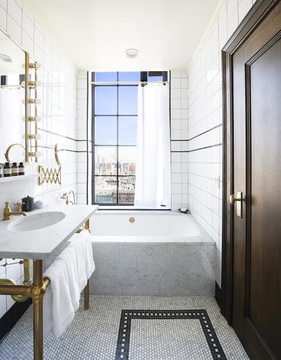 A bathroom with a tub, sink and mirror.