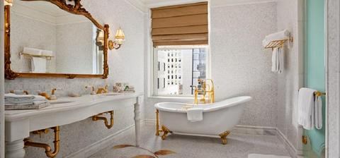 A bathroom with a tub, sink and mirror.