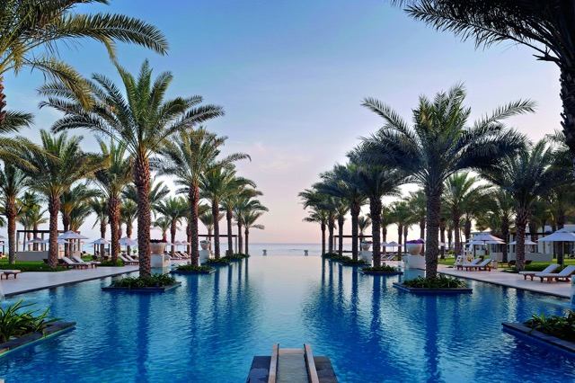 A pool with palm trees and a dock in the middle.