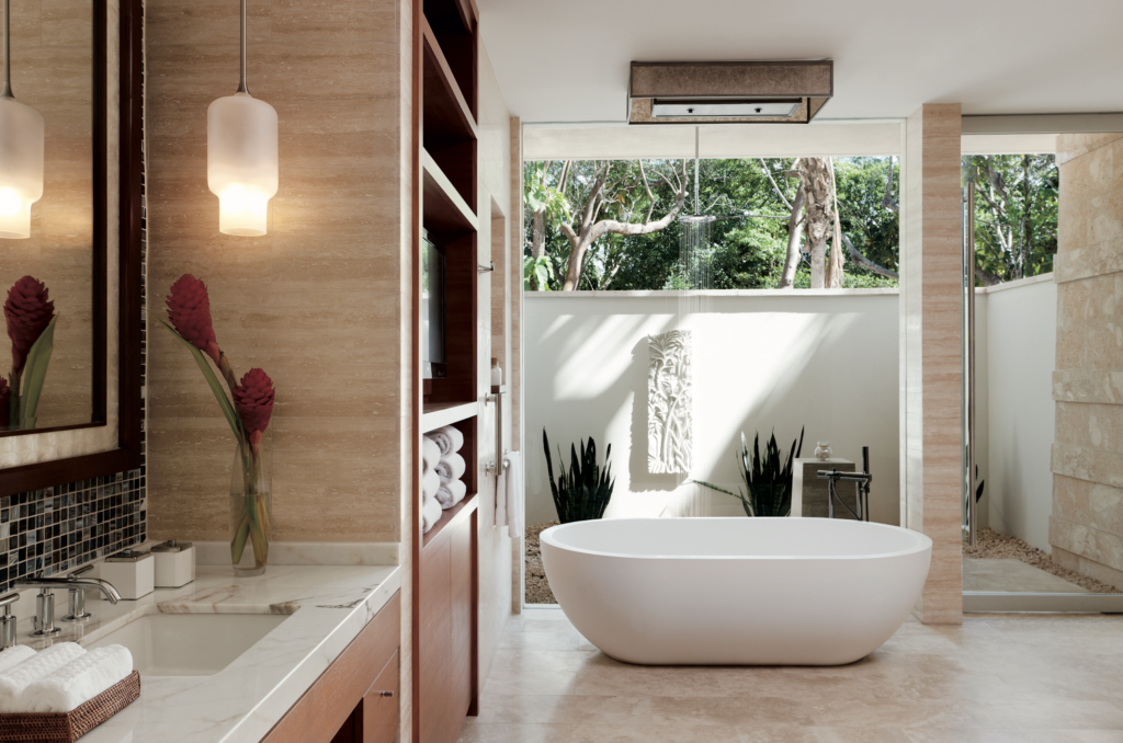 A bathroom with a large window and a white tub.