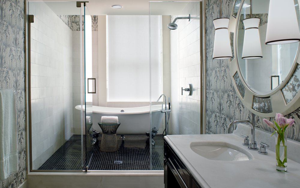 A bathroom with a tub, sink and mirror.