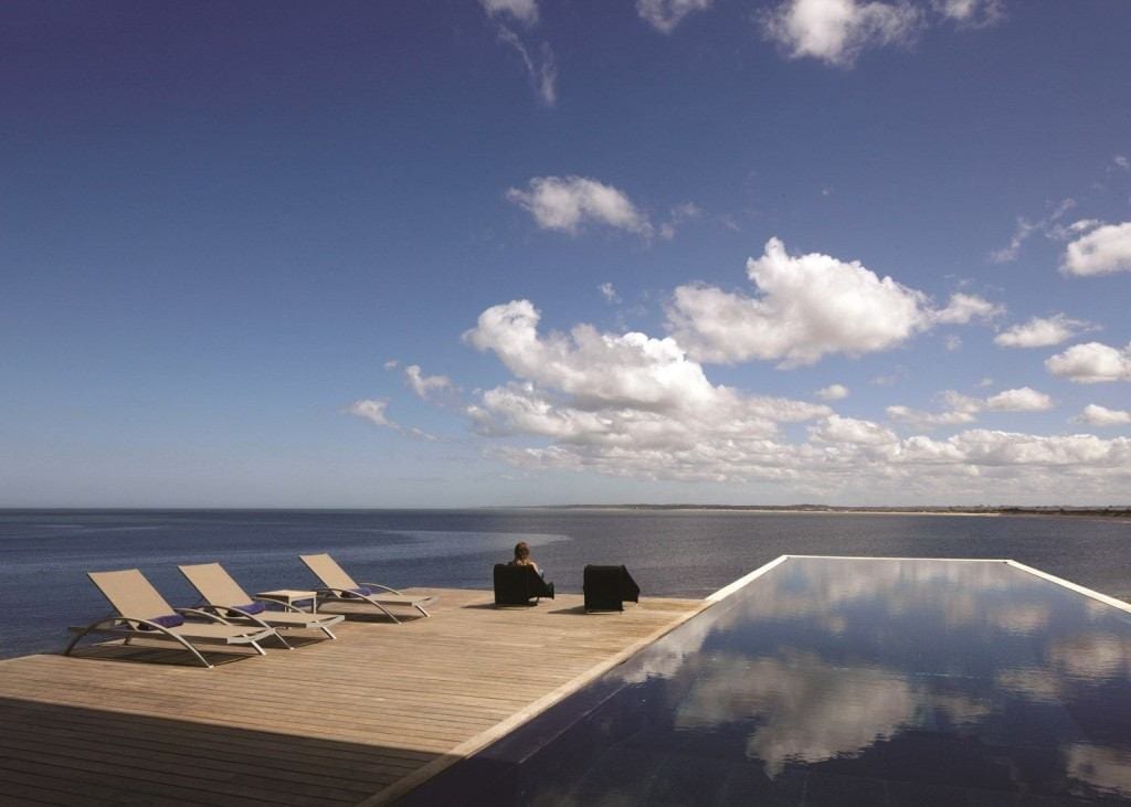 A person sitting on the edge of an infinity pool.