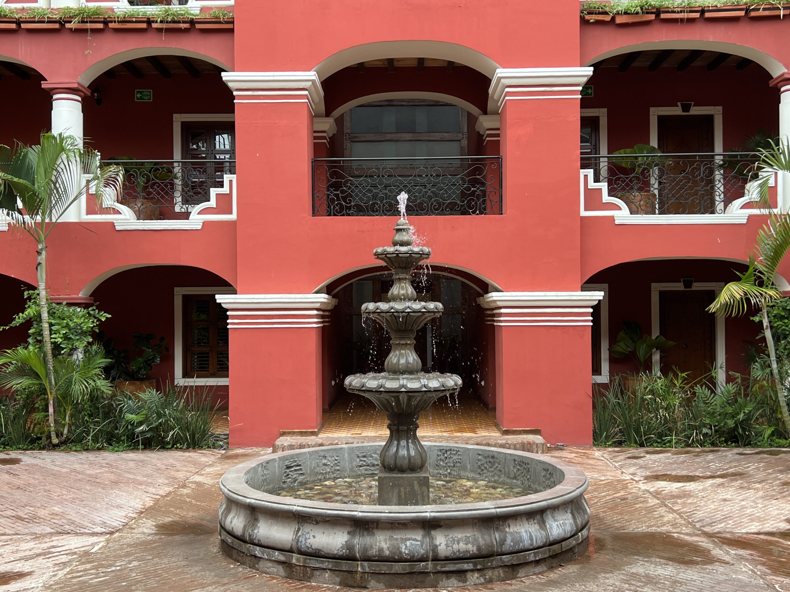 A fountain in front of a red building with balconies.