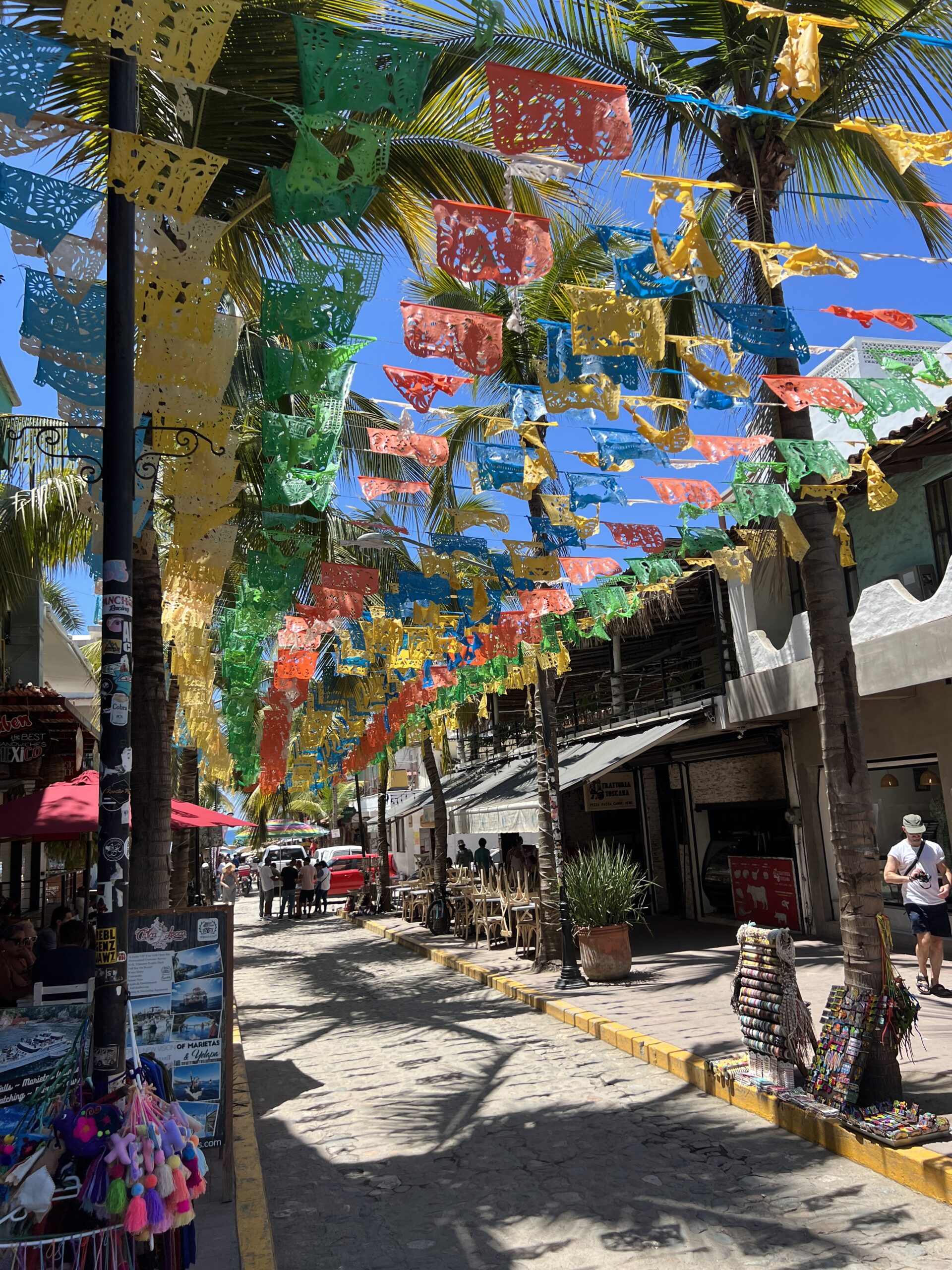 A street with many colorful decorations hanging from the trees.