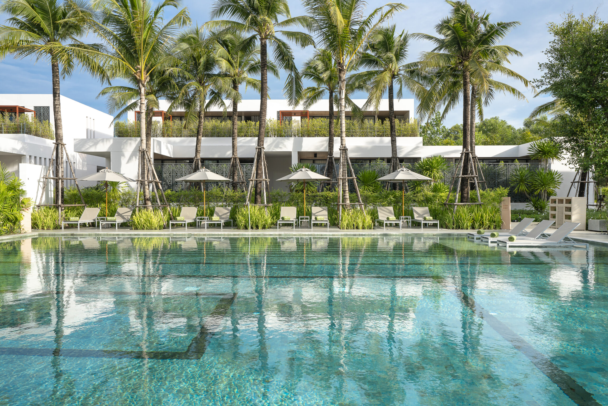 A pool with palm trees and a building in the background