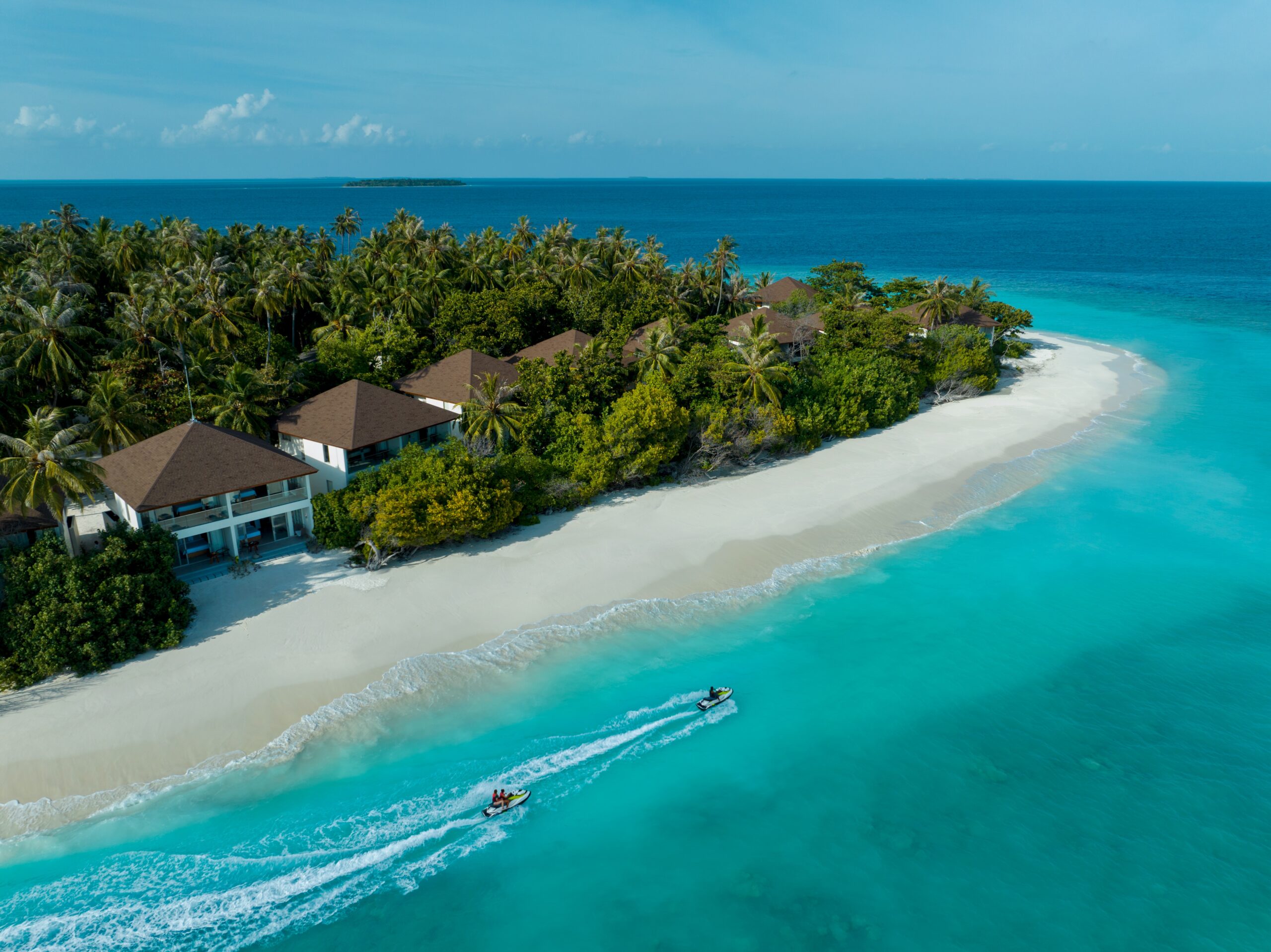 A boat is traveling down the beach near some houses.