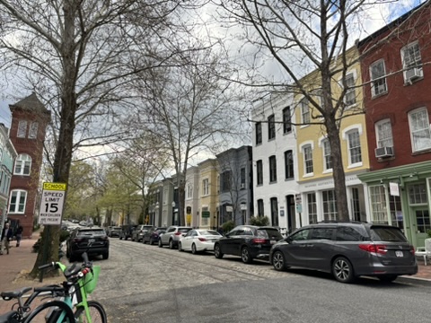 A street with parked cars and bicycles on the side.