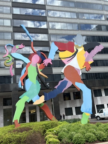 A large sculpture of two people in front of a building.