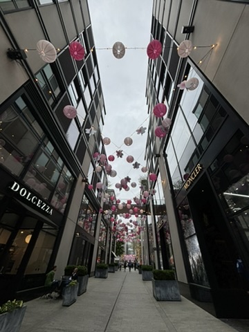 A street with many pink balloons hanging from the ceiling.